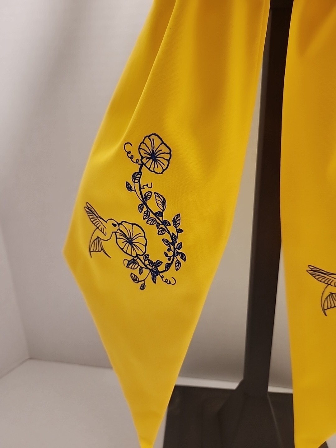 Wreath Sash In This Bright Yellow Color Emboidered With A Humming Bird In Navy