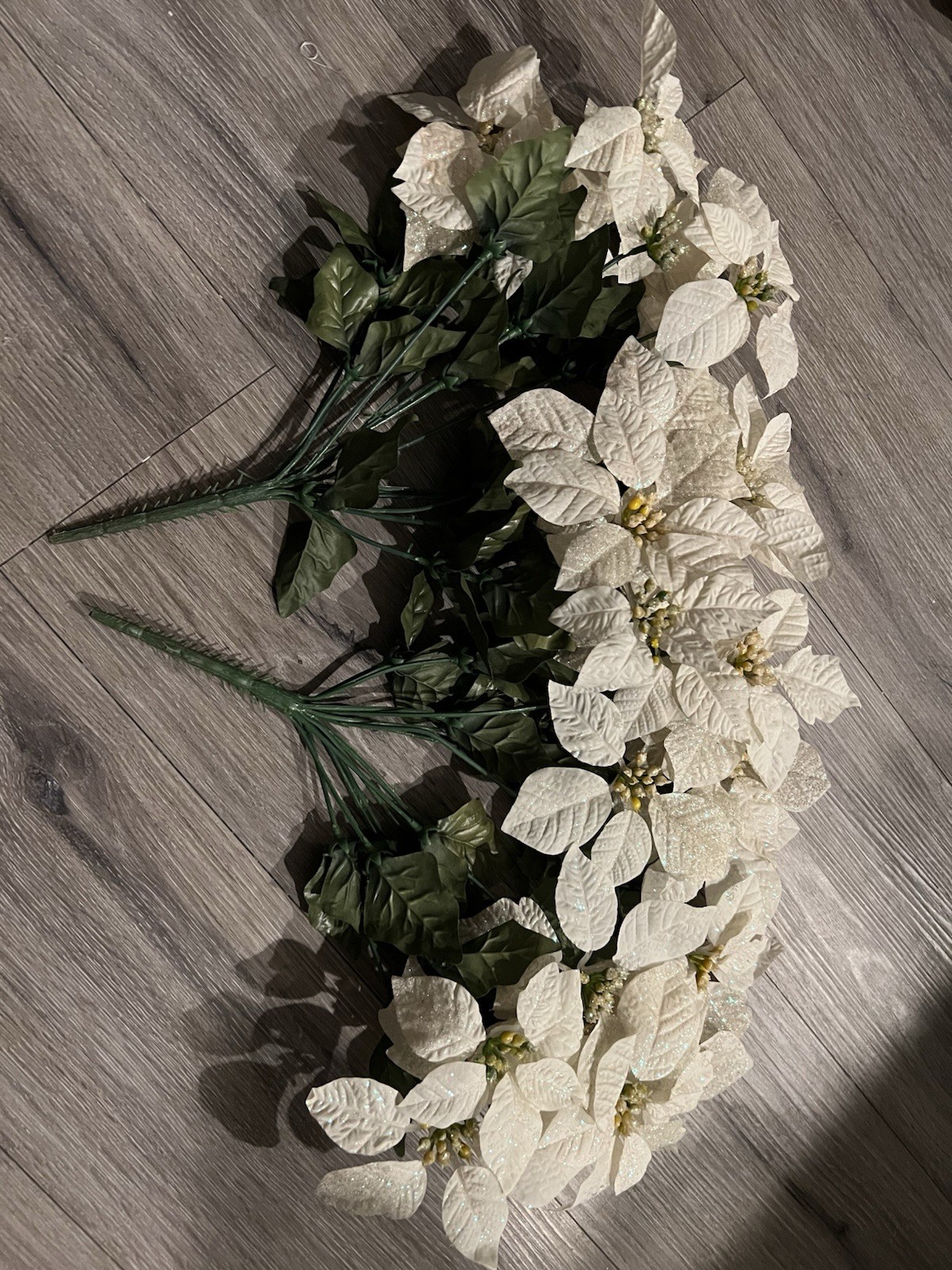 2 artificial white poinsettia bushes with green leaves and sparkle details