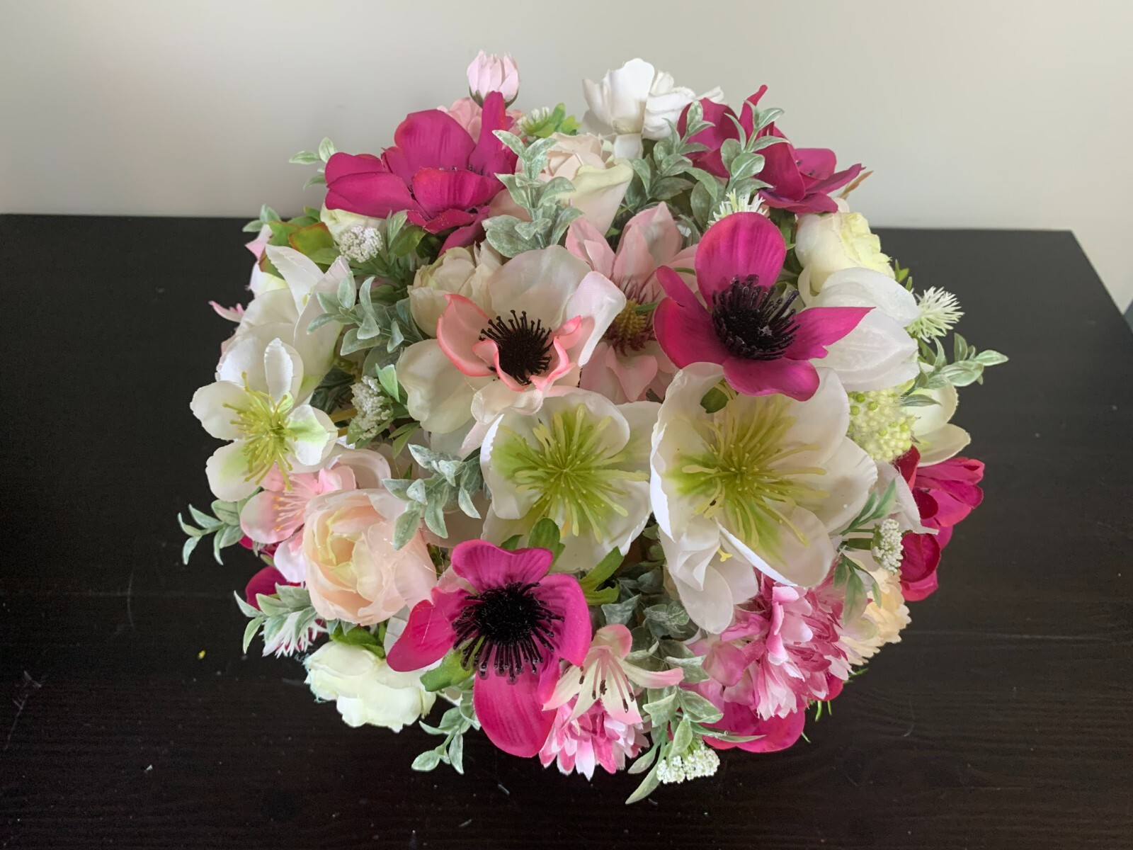 Flower arrangement of artificial flowers in a black glass vase  size 11x10x11