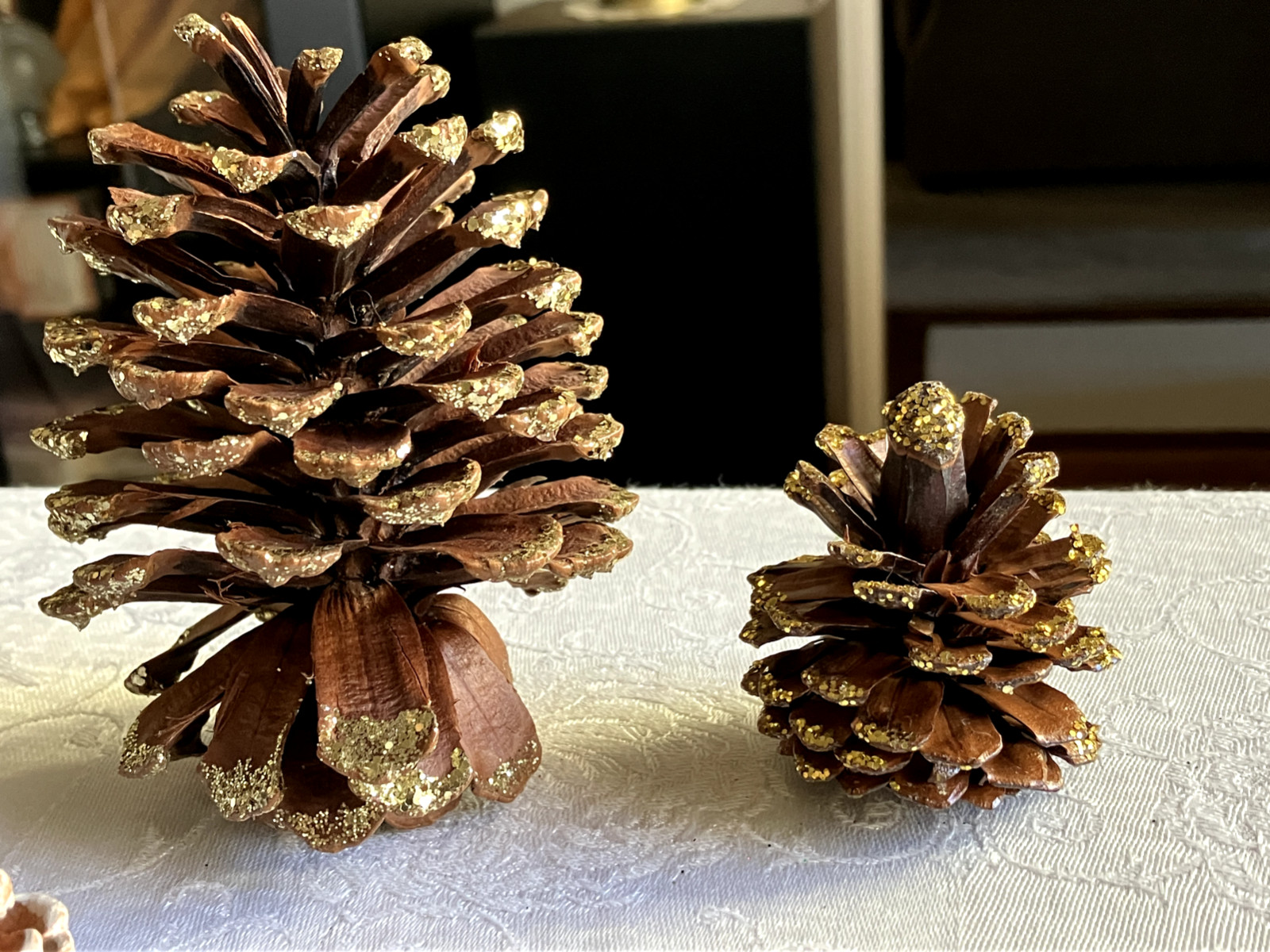LOT OF 5 PINE CONES DECORATED IN WHITE AND GOLD IN VARIOUS SIZES FROM 2 IN-4.5IN