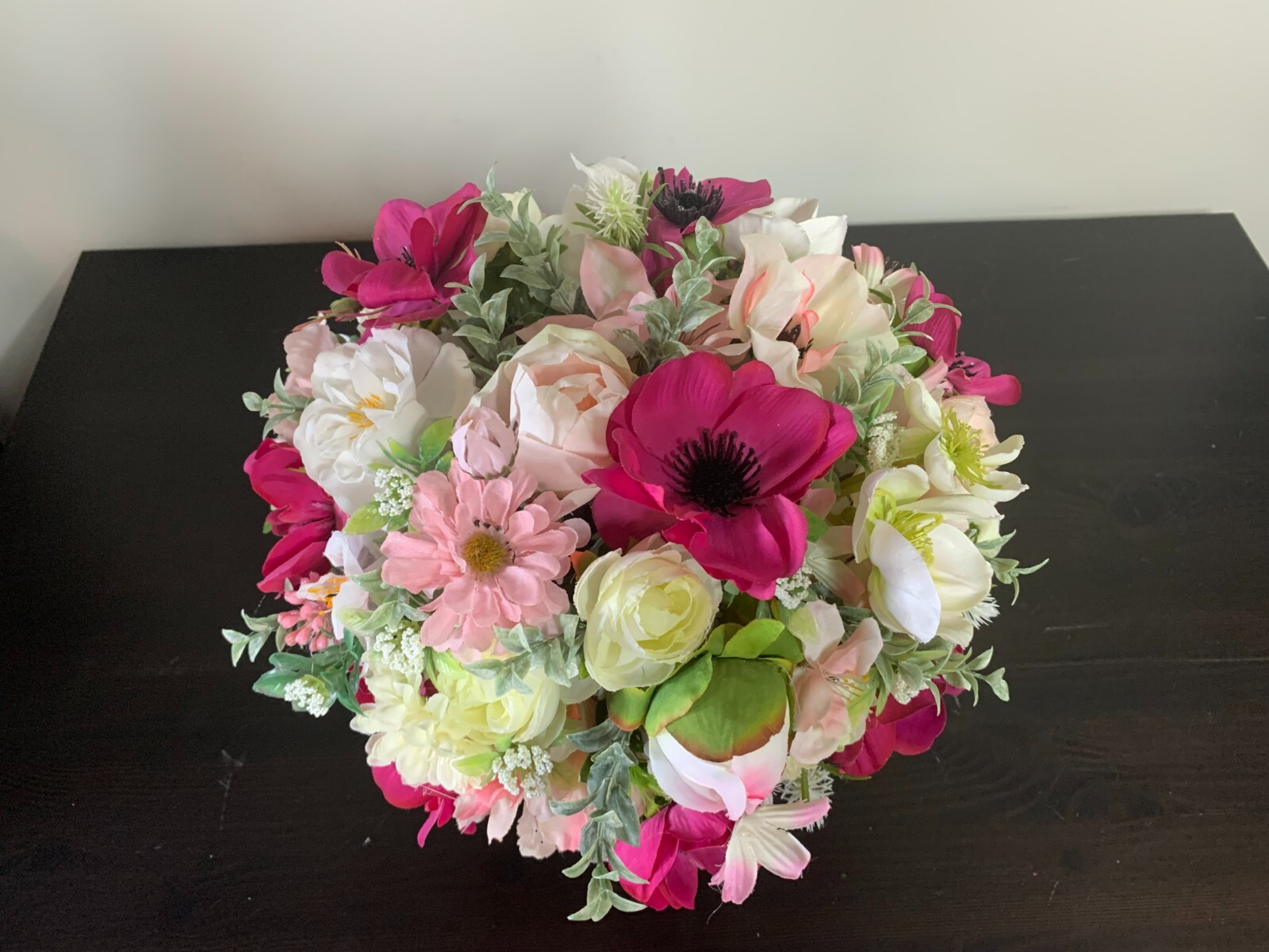 Flower arrangement of artificial flowers in a black glass vase  size 11x10x11