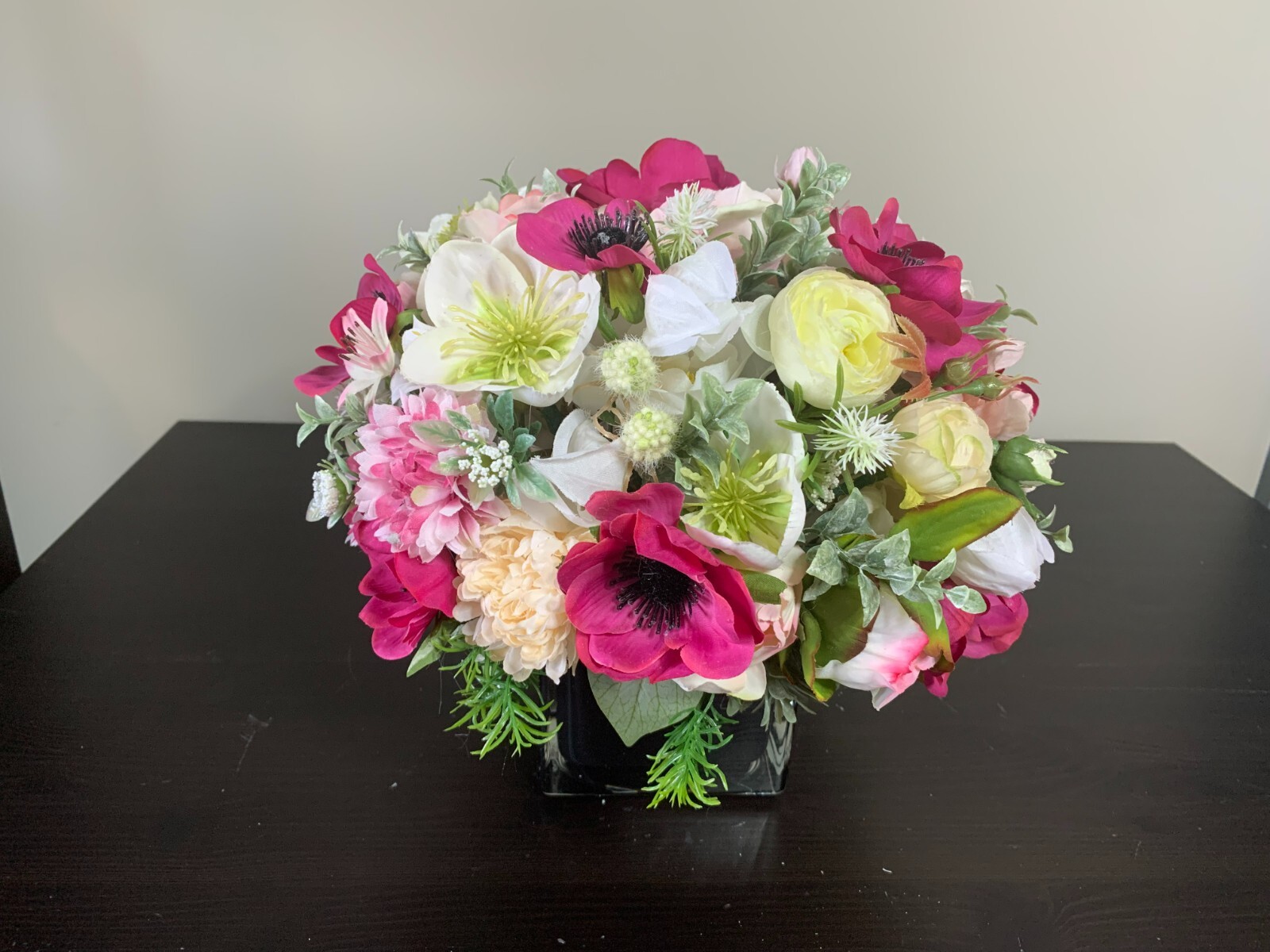 Flower arrangement of artificial flowers in a black glass vase  size 11x10x11