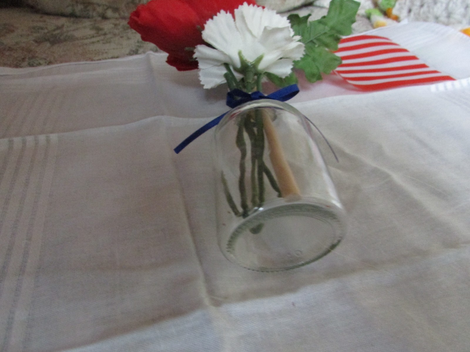 red, white, and blue fake flower bouquet, with small glass vase, and small flag