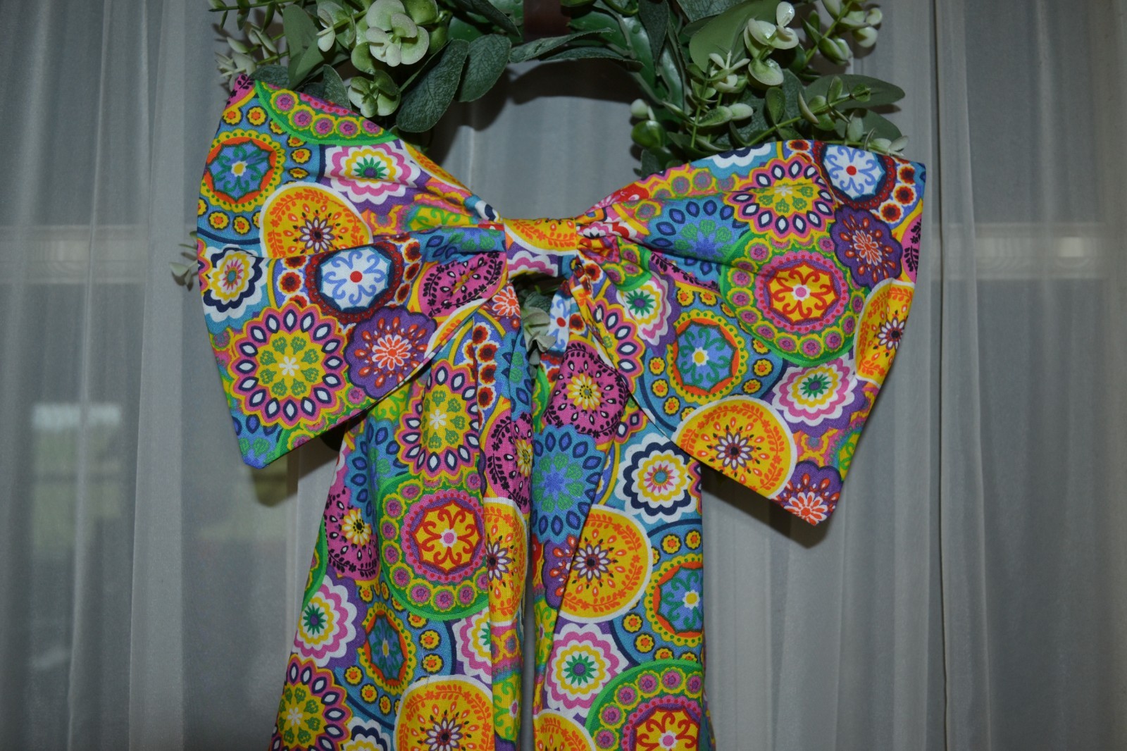 Wreath sash with bow in a colorful kalidescope pattern