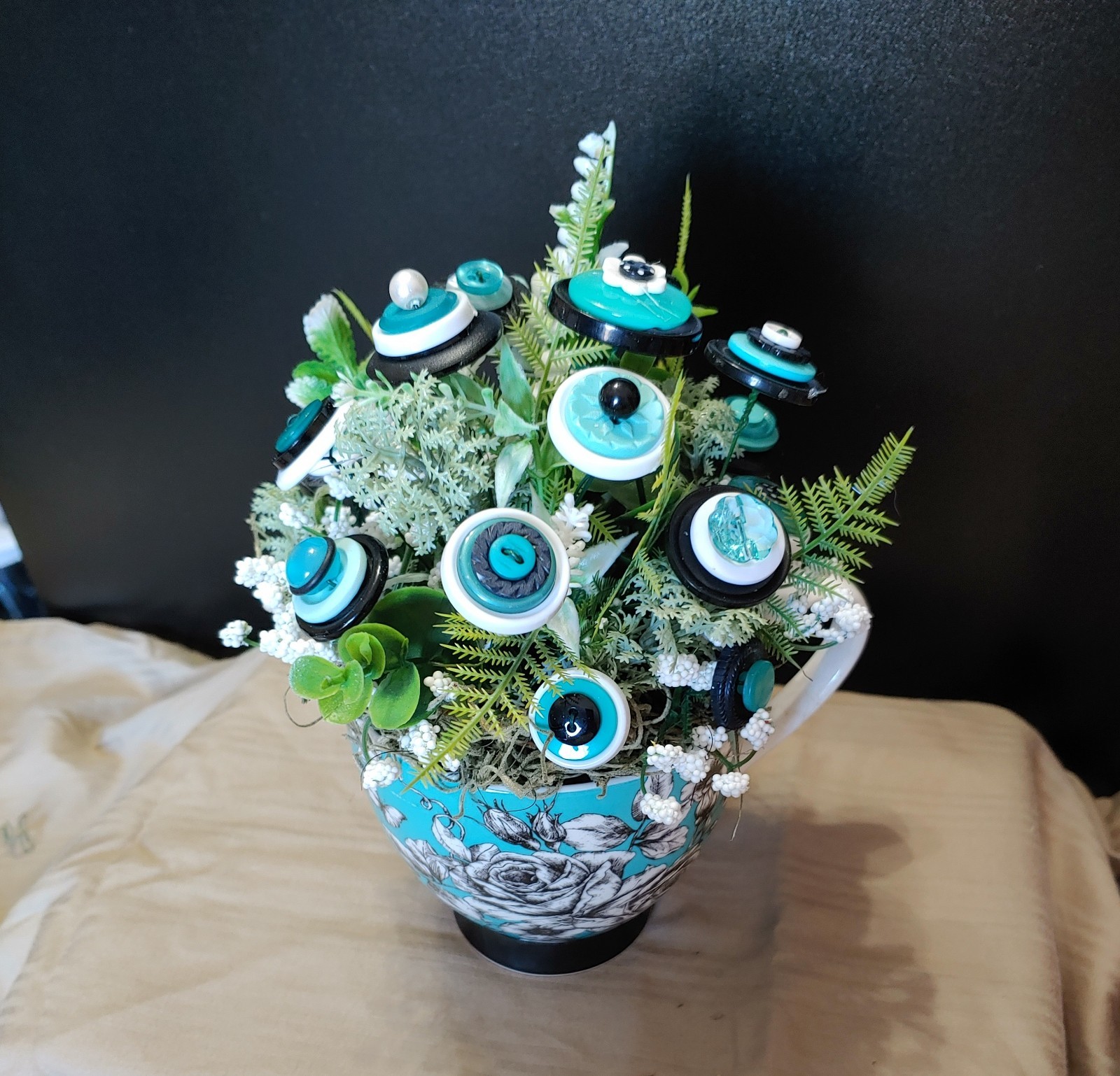 BUTTON BOUQUET IN matching turquoise, black, and white floral mug.