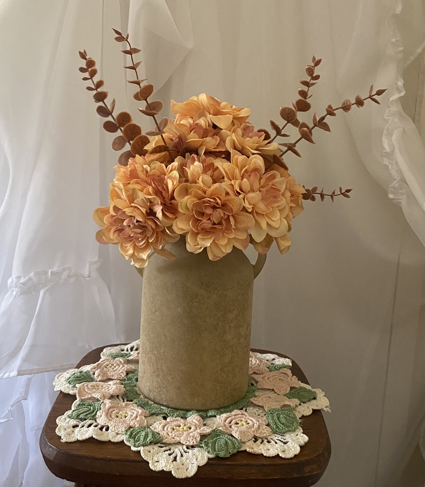 Orange Peach Dahlias accented with Brown Eucalyptus in a Beige Sandstone Vase