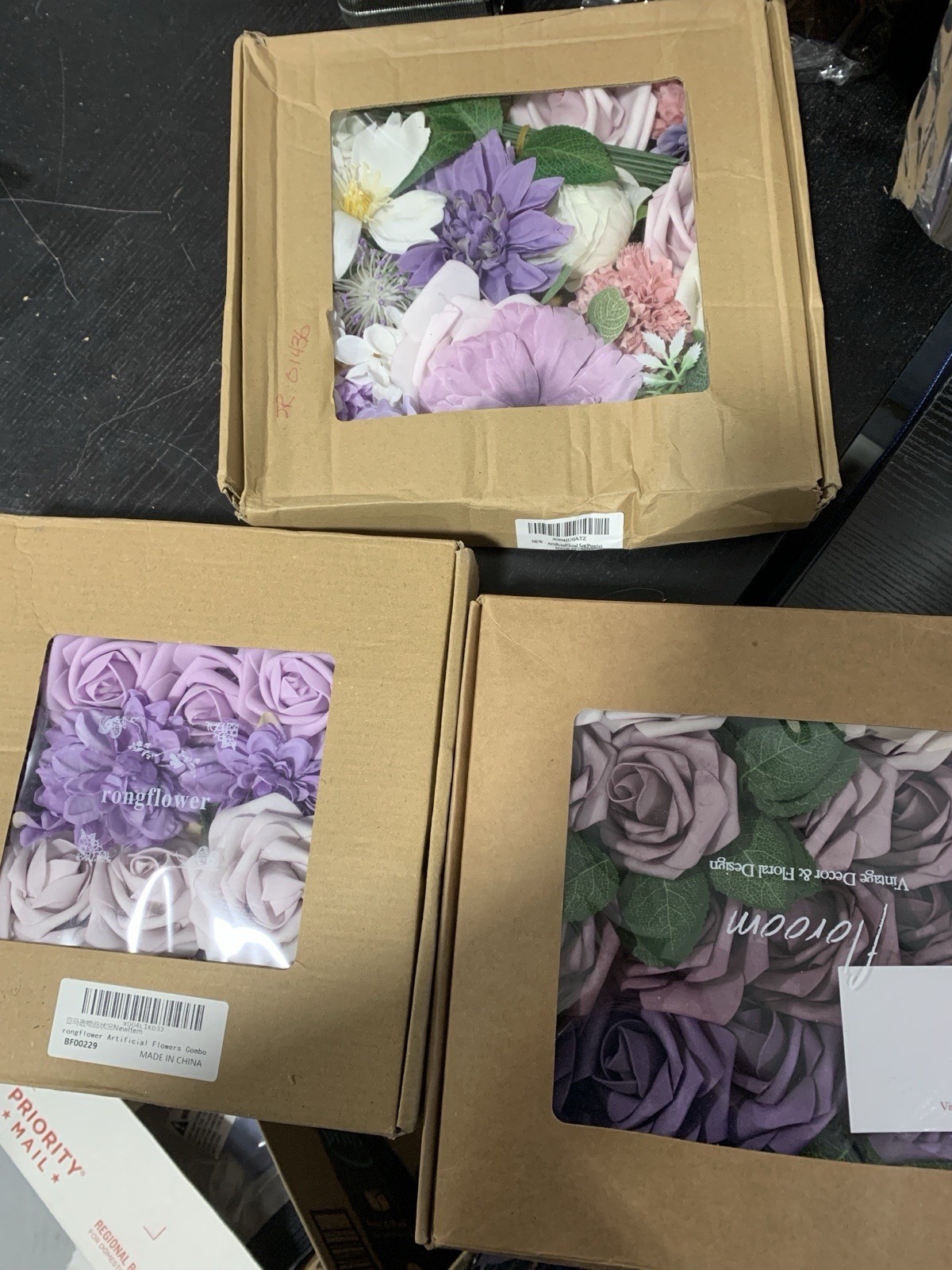 3 boxes of a variety of purple artificial flower heads aprox 3 dozen