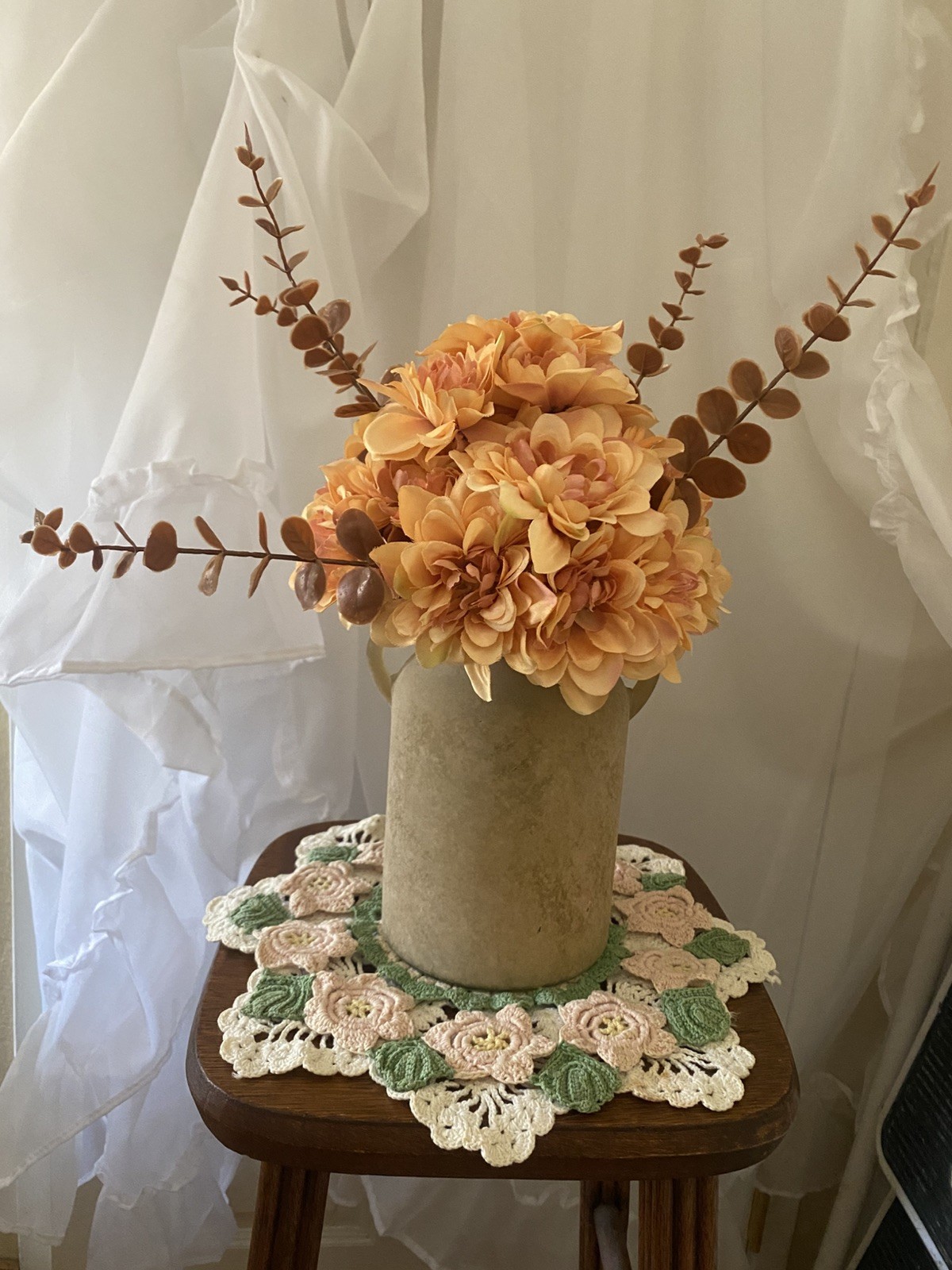 Orange Peach Dahlias accented with Brown Eucalyptus in a Beige Sandstone Vase