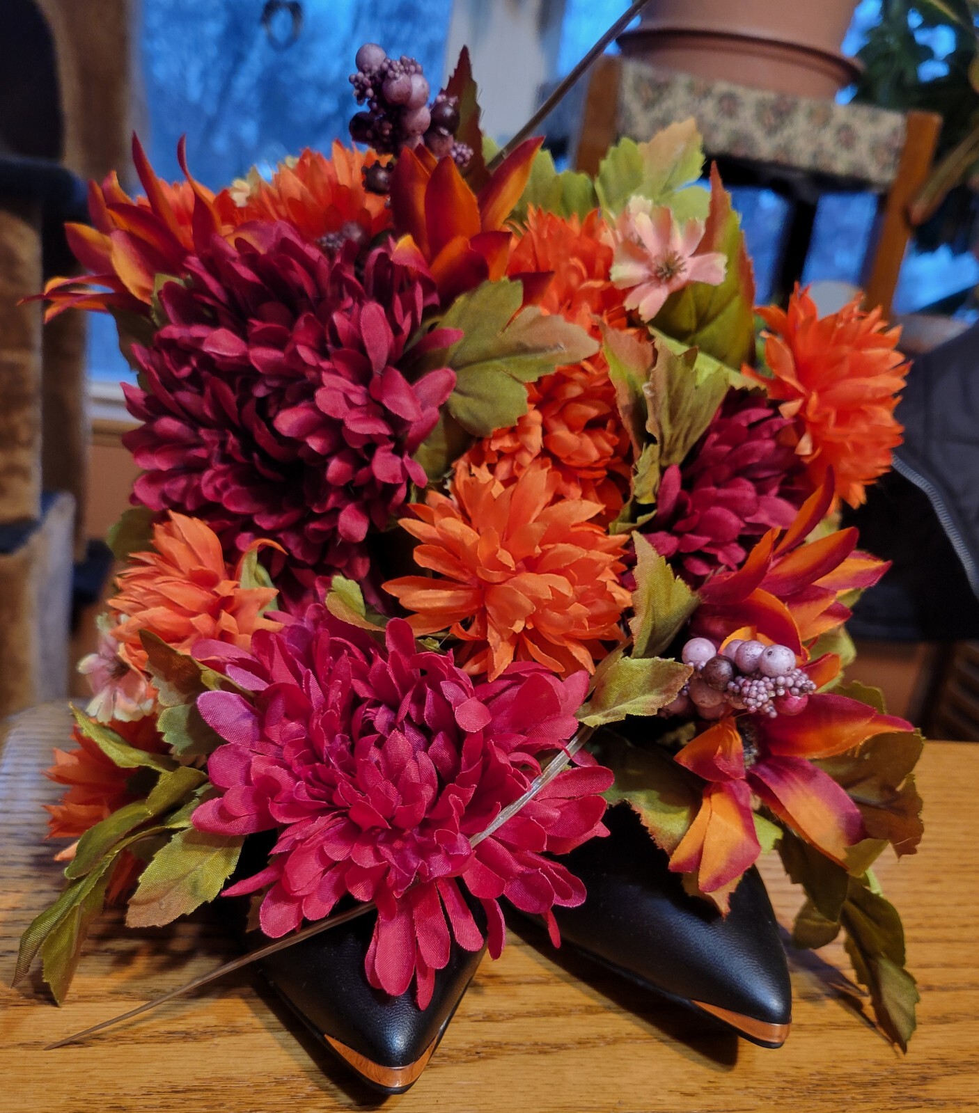 Floral Shoe Arrangement. Orange, Dark Red Flowers in Black Heels with Gold Trim.
