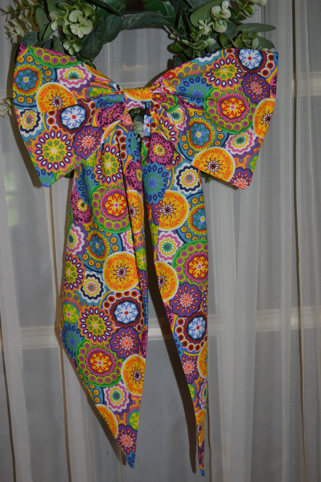 Wreath sash with bow in a colorful kalidescope pattern