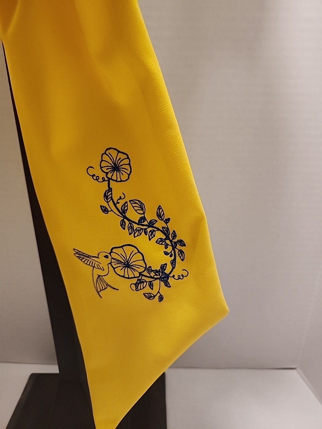 Wreath Sash In This Bright Yellow Color Emboidered With A Humming Bird In Navy