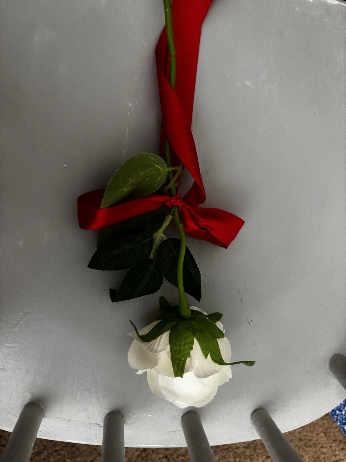 Faux White Rose With Green Stem And Leaves With Red Ribbon Tied Around Stem
