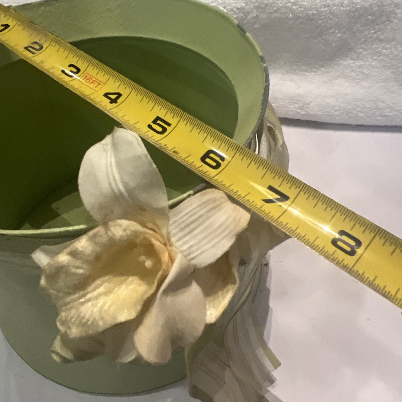 Green metal bucket decorated with a ribbon and artificial flowers