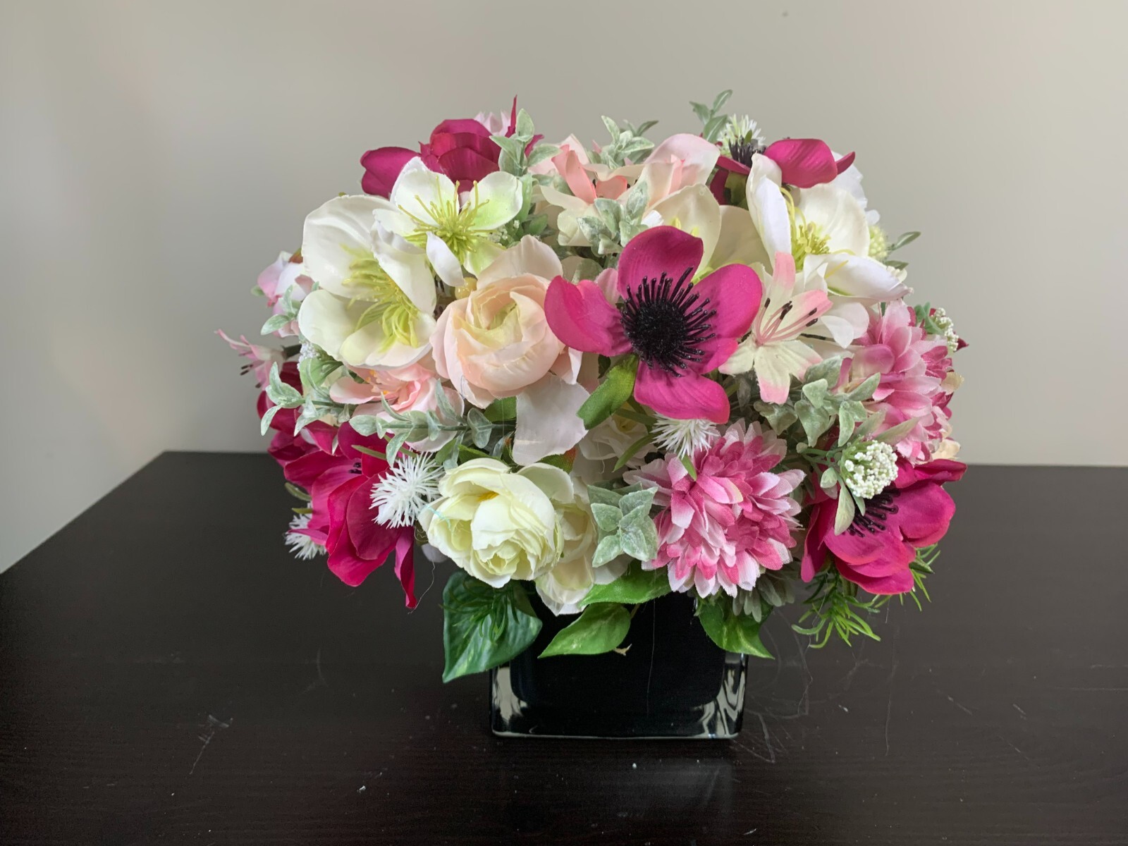 Flower arrangement of artificial flowers in a black glass vase  size 11x10x11