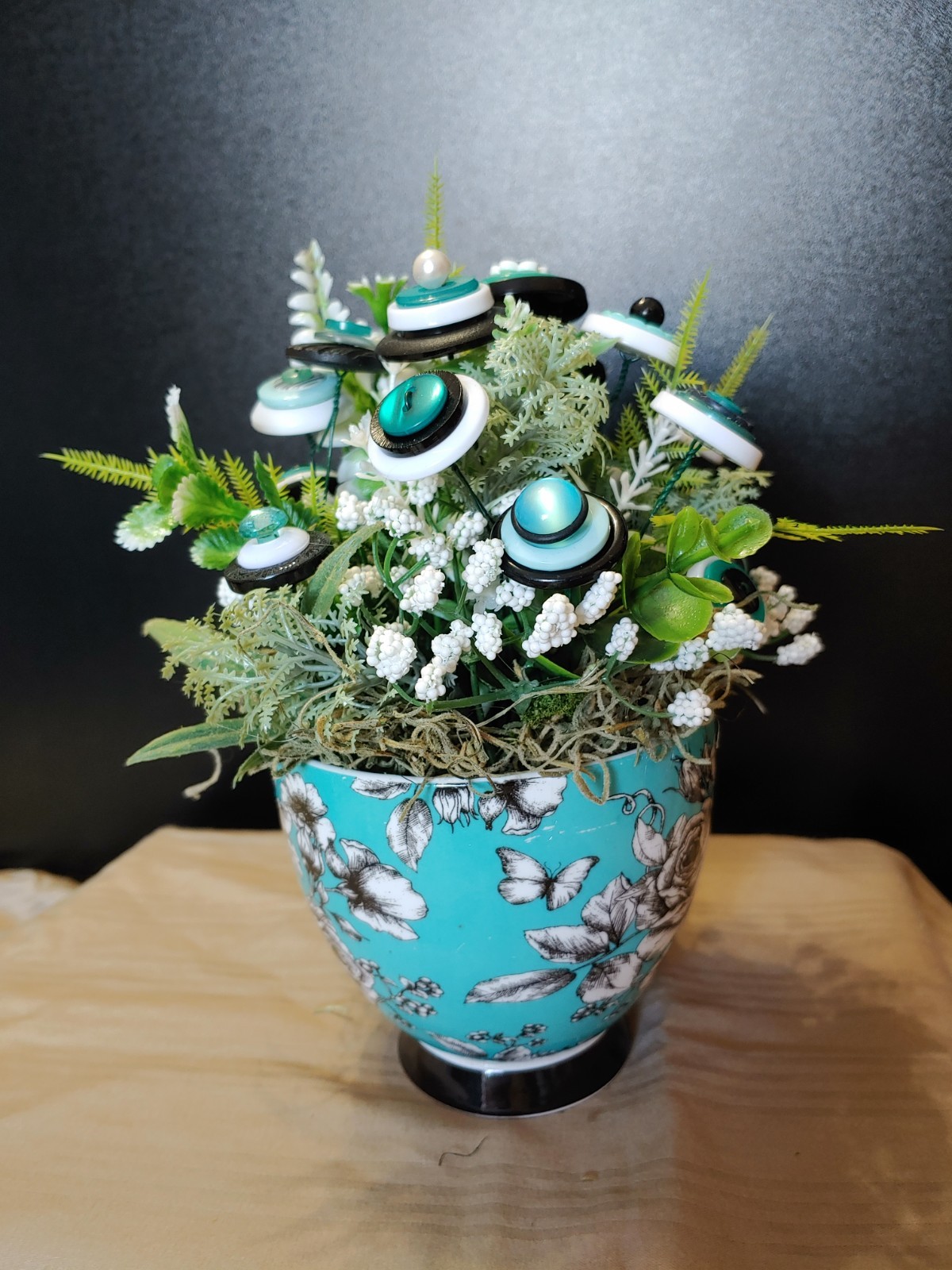 BUTTON BOUQUET IN matching turquoise, black, and white floral mug.