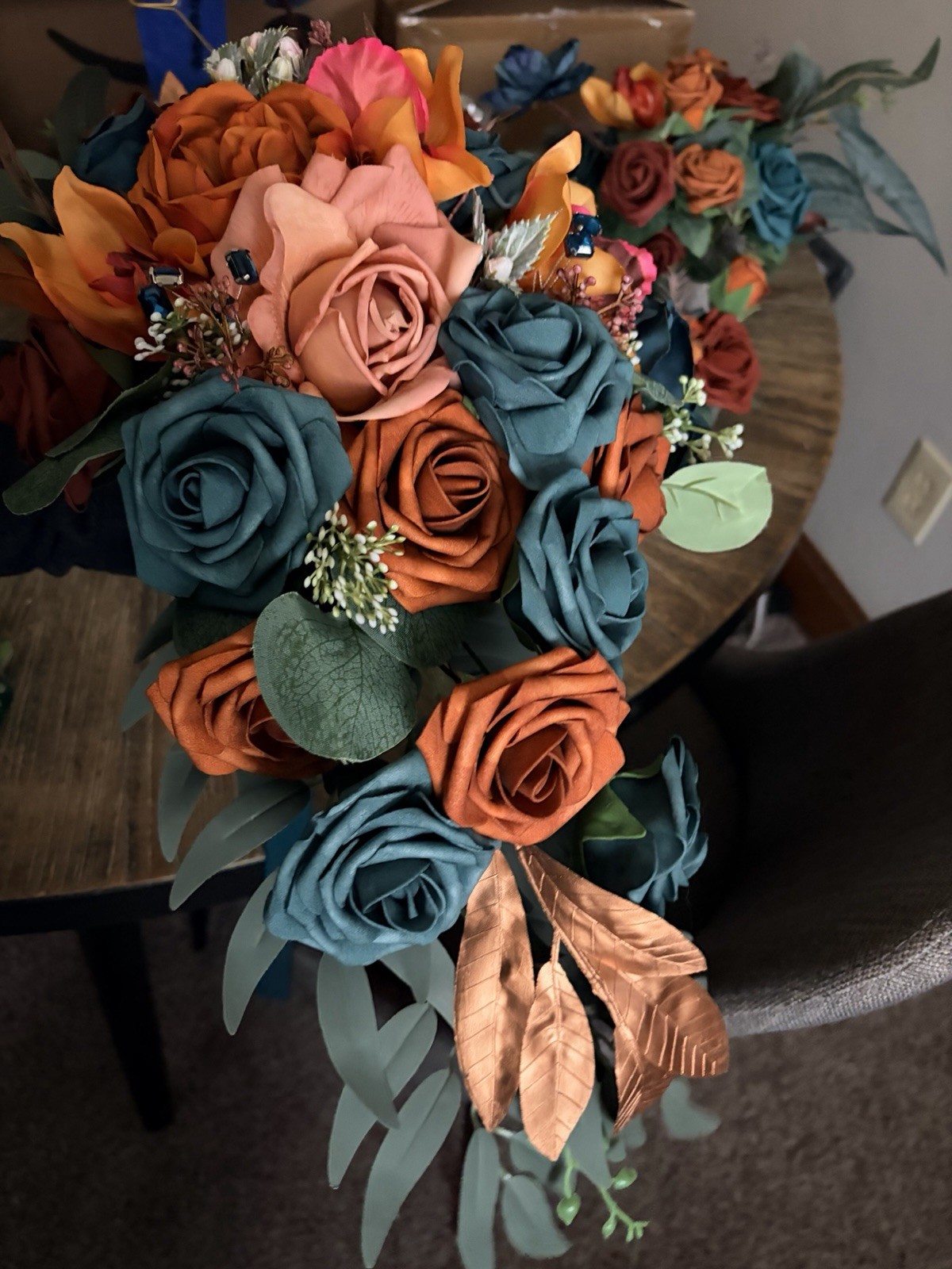 Teal & burnt orange centerpieces, bridal bouquet, and boutonnière. Lings flowers