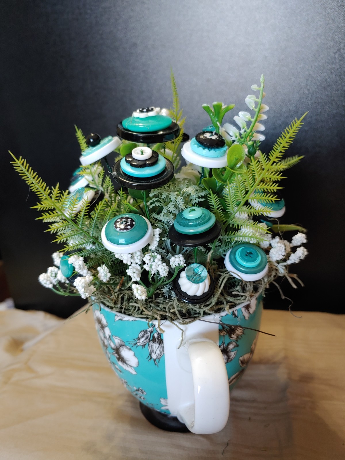 BUTTON BOUQUET IN matching turquoise, black, and white floral mug.