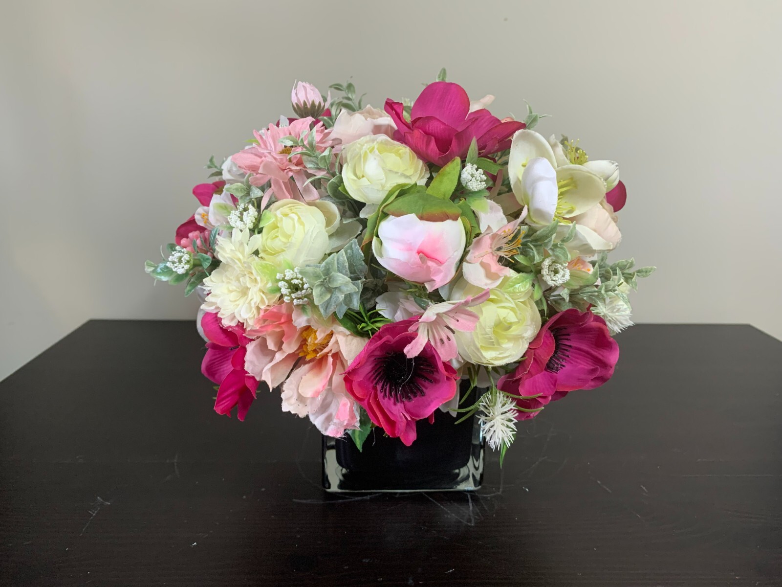 Flower arrangement of artificial flowers in a black glass vase  size 11x10x11