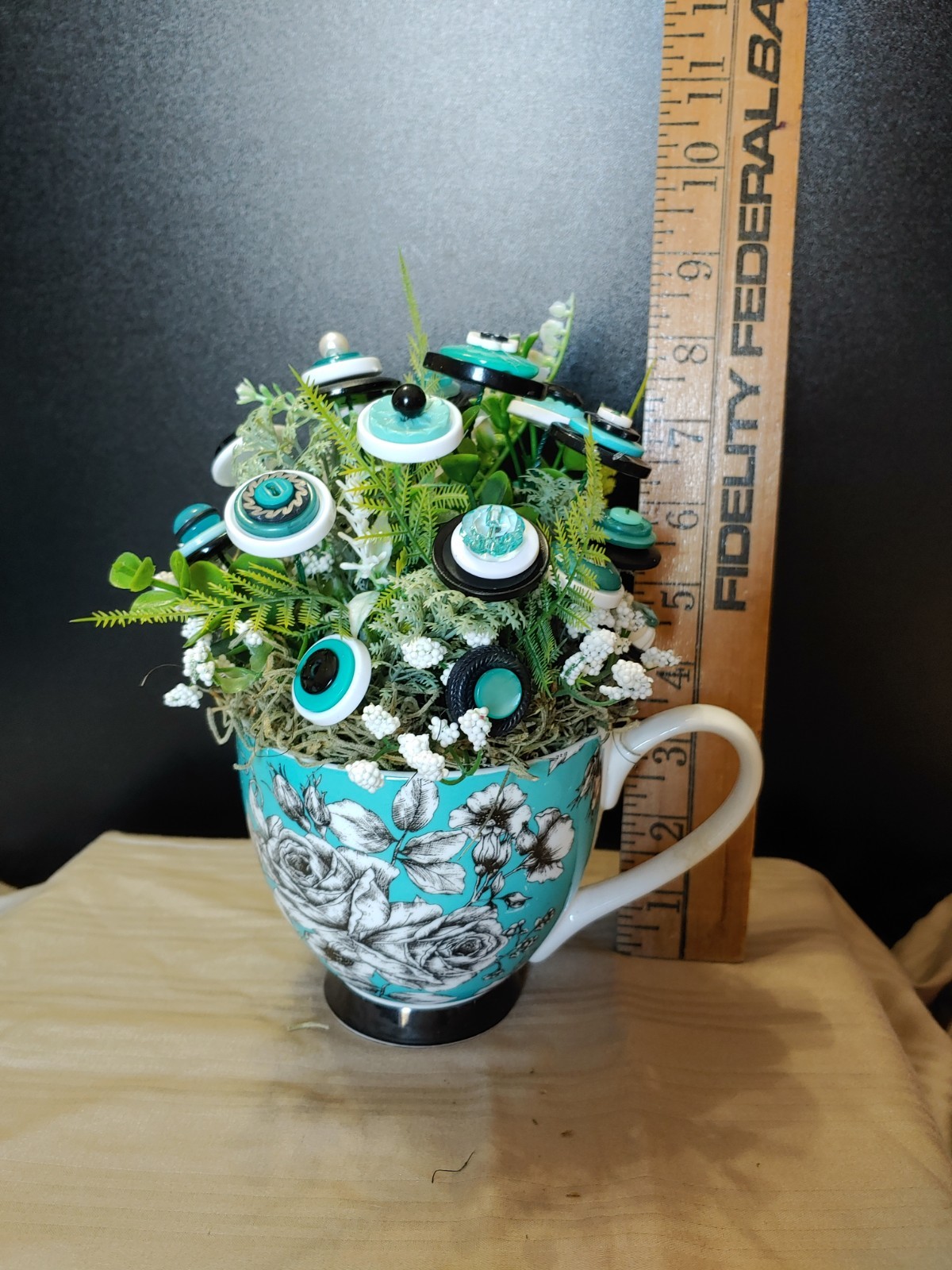 BUTTON BOUQUET IN matching turquoise, black, and white floral mug.