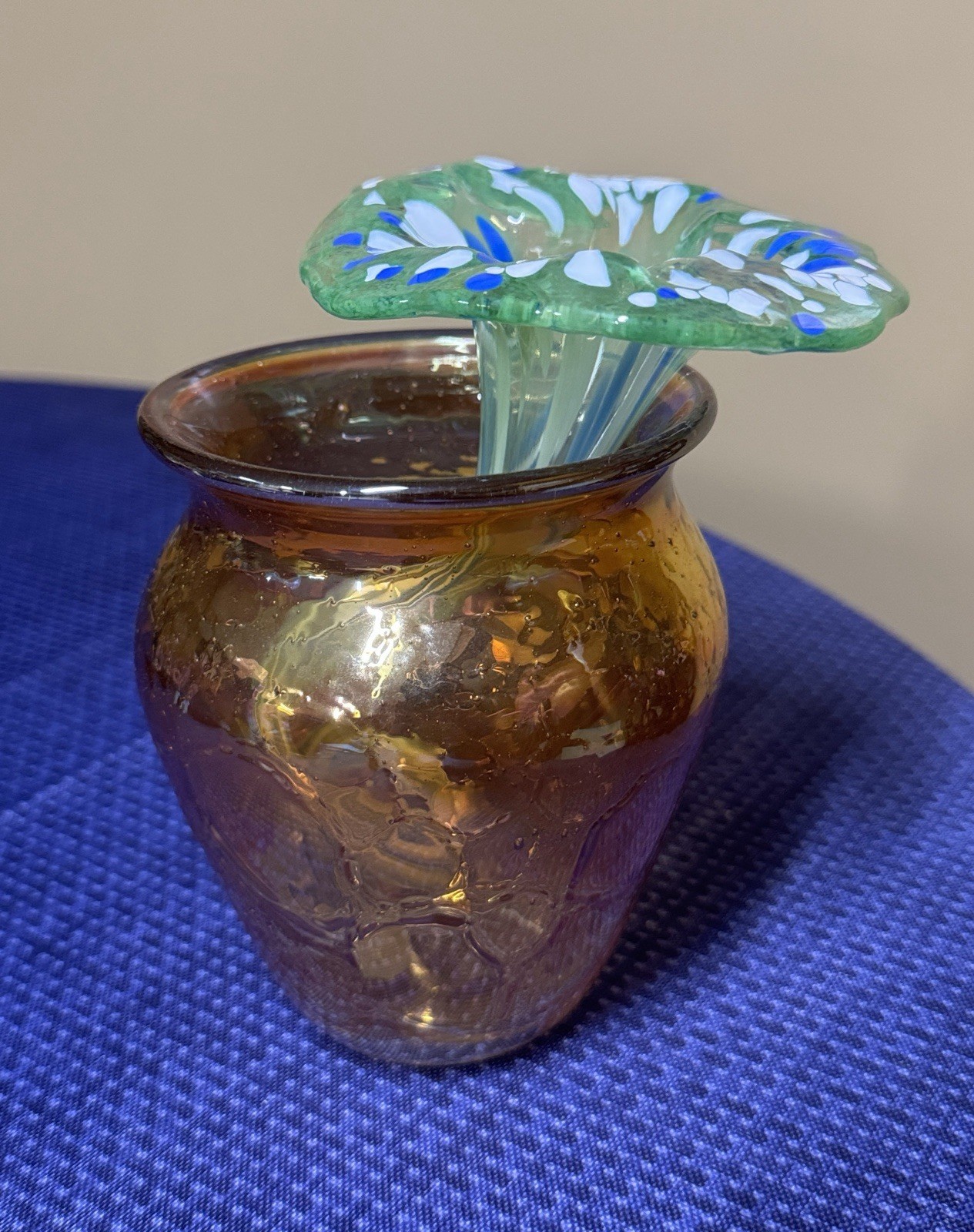 blown glass flower with a speckled green, blue, and white color, curly stem 7”
