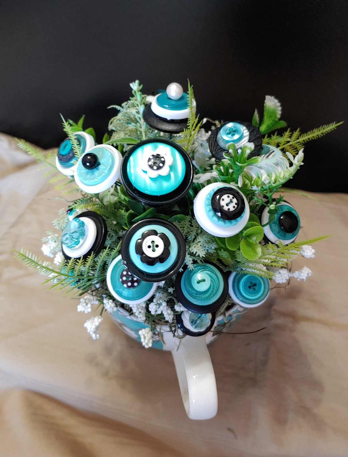 BUTTON BOUQUET IN matching turquoise, black, and white floral mug.