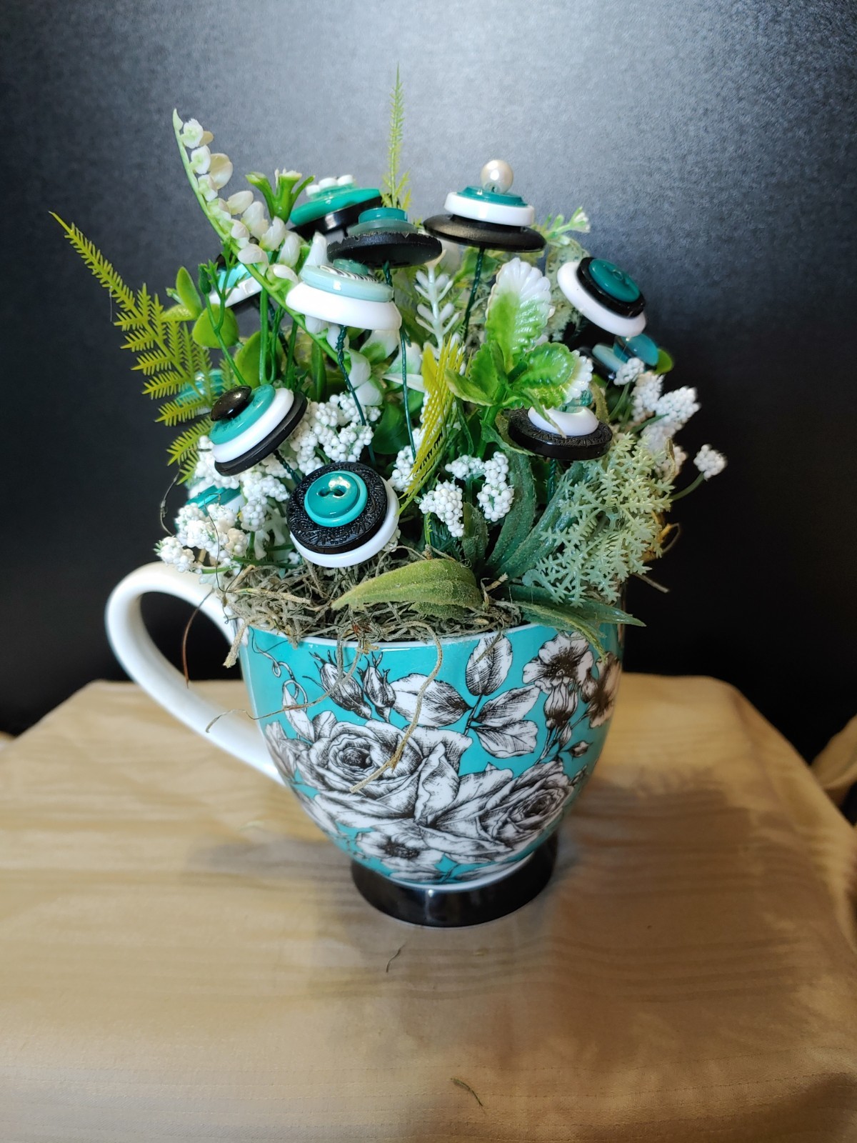 BUTTON BOUQUET IN matching turquoise, black, and white floral mug.