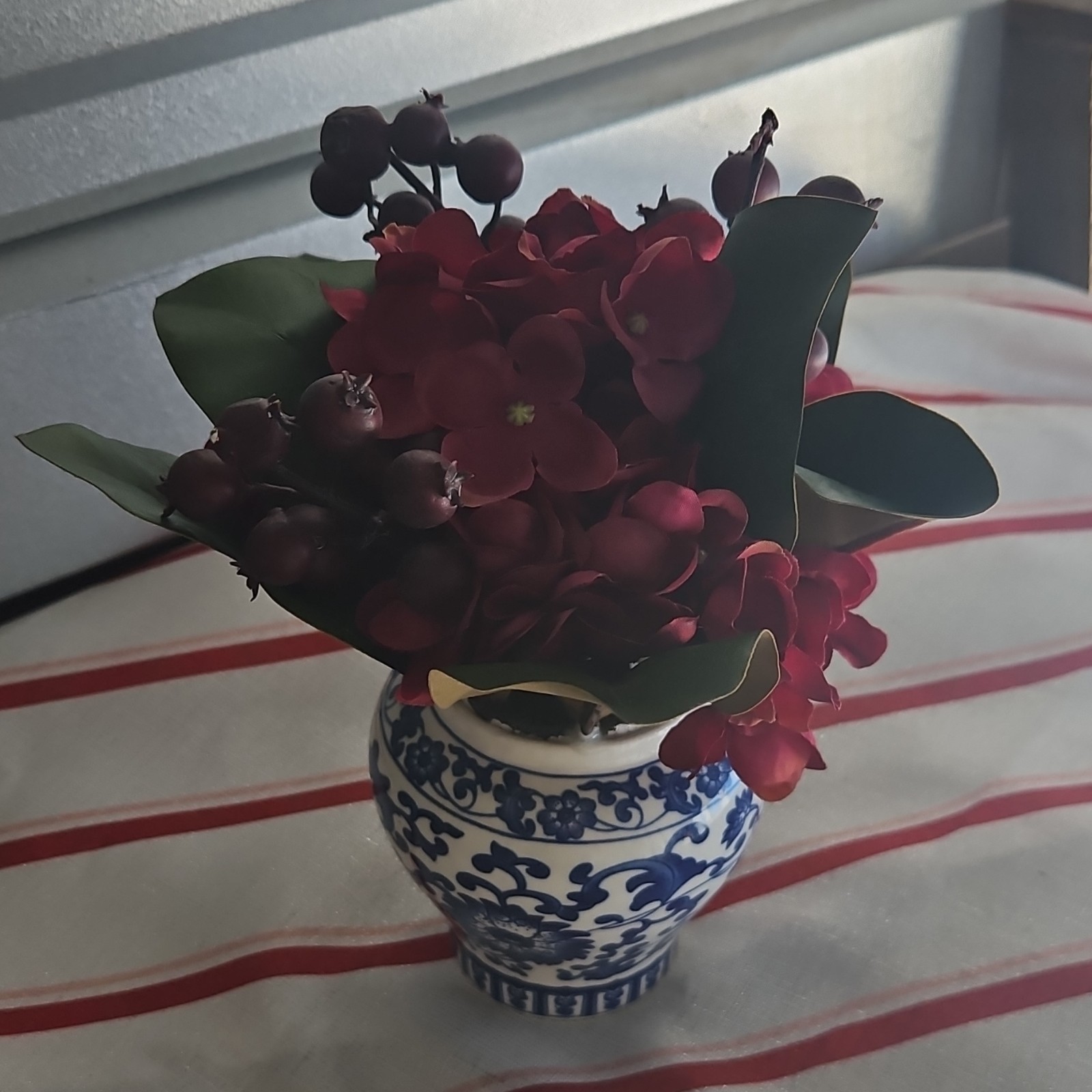 Artificial Red and Green Flower Arrangement Centerpiece in Blue and White Vase