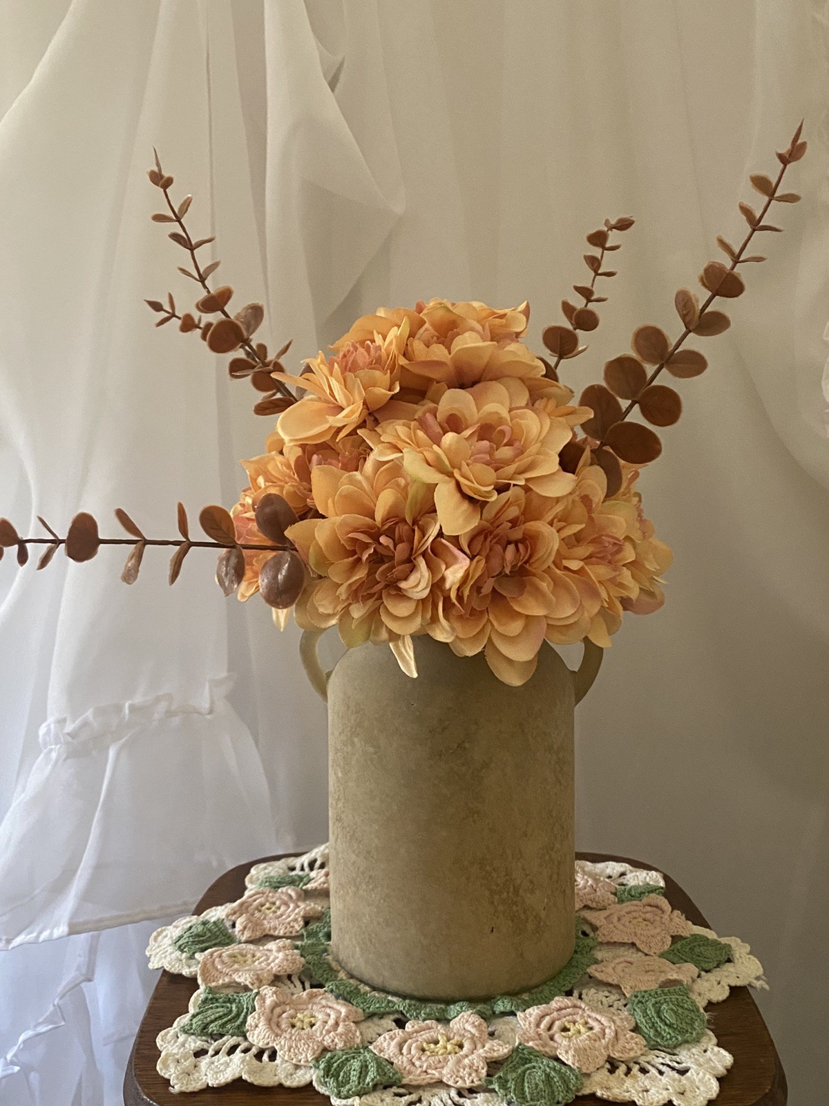Orange Peach Dahlias accented with Brown Eucalyptus in a Beige Sandstone Vase