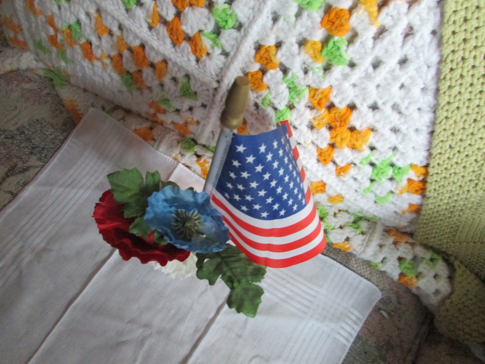 red, white, and blue fake flower bouquet, with small glass vase, and small flag