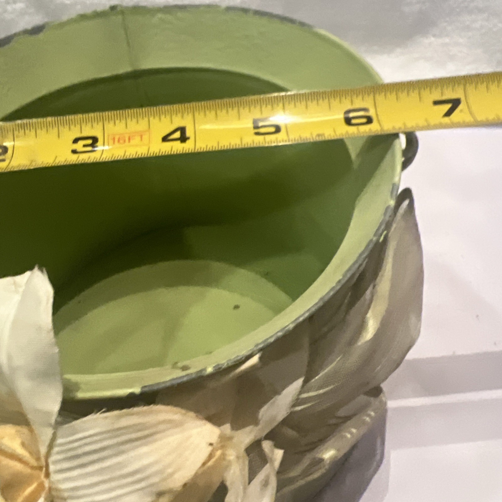 Green metal bucket decorated with a ribbon and artificial flowers