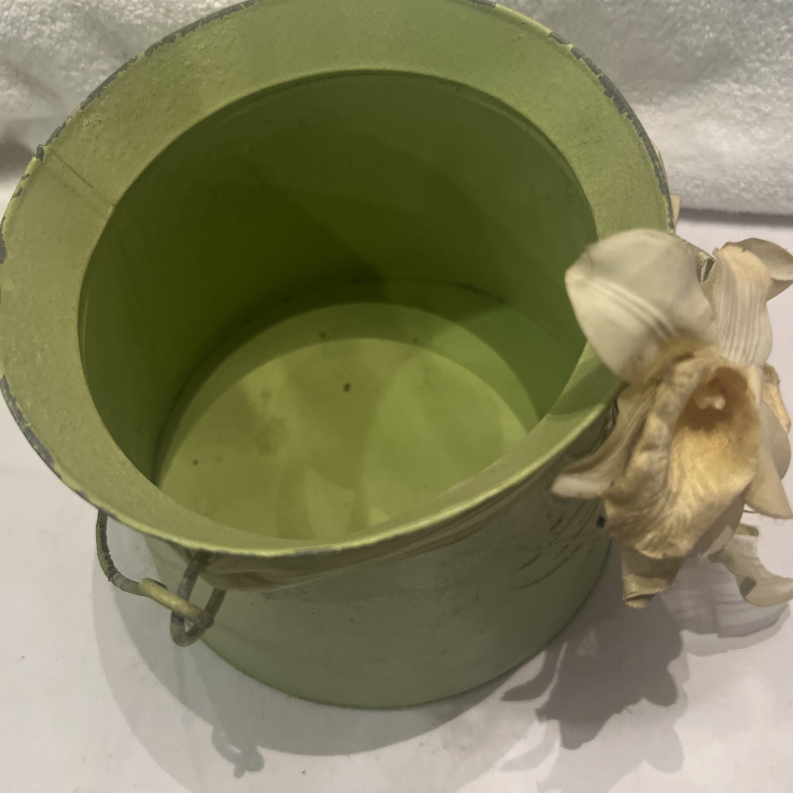 Green metal bucket decorated with a ribbon and artificial flowers